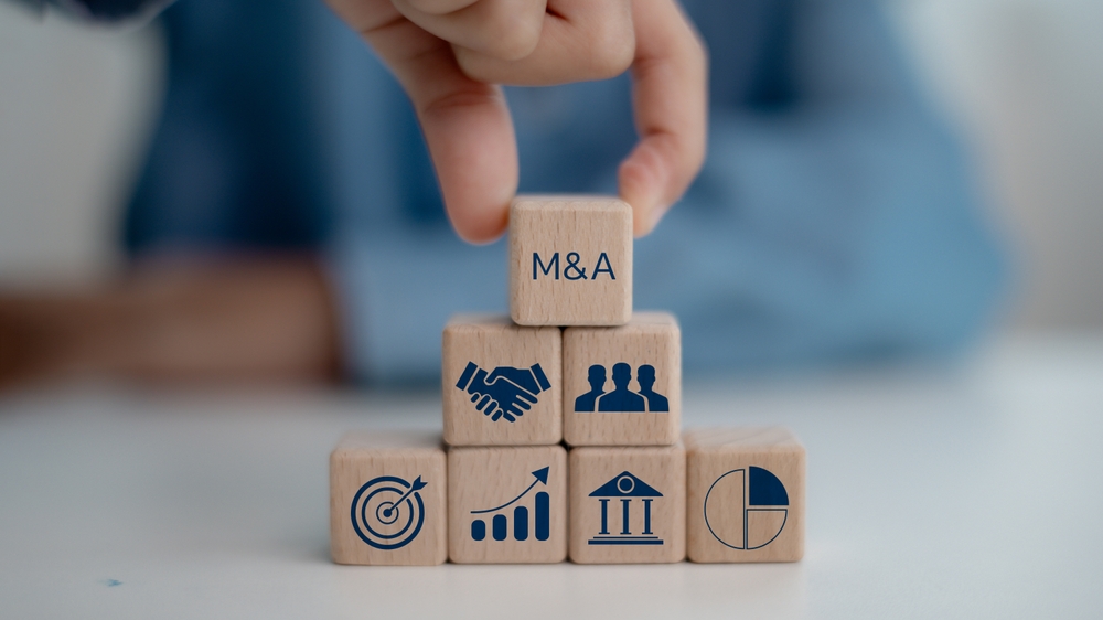 Wooden blocks representing a business merger and acquisition with M&A, partnership, growth, and finance icons.