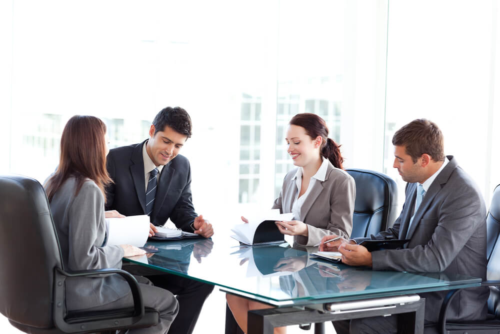 Business people involved in an acquisition around a table working out the details.