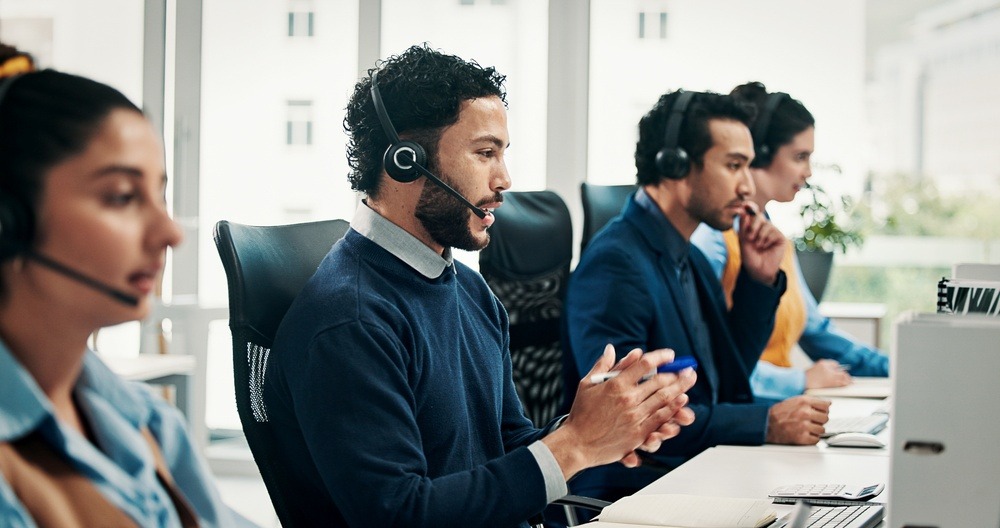 Insurance agents wearing headsets assist customers in a modern call center using human expertise alongside AI tools