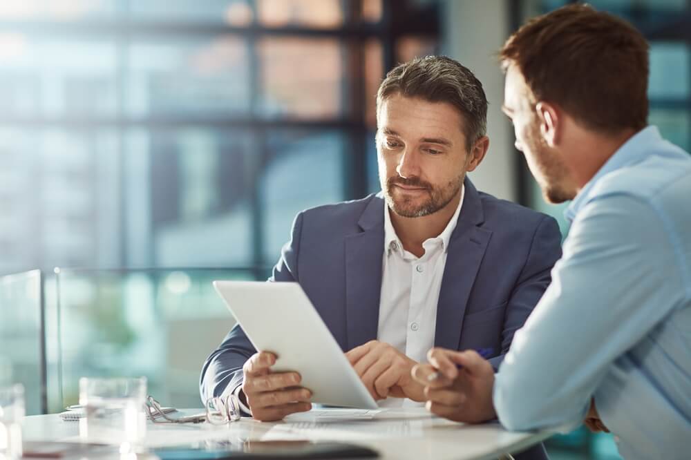 Two insurance professionals reviewing data on a tablet, reflecting the future of insurance with AI-powered decision-making.