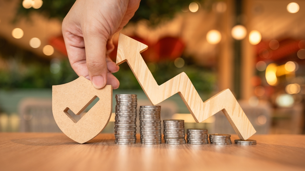 Insurance business growth concept with a shield, stacked coins, and an upward arrow.